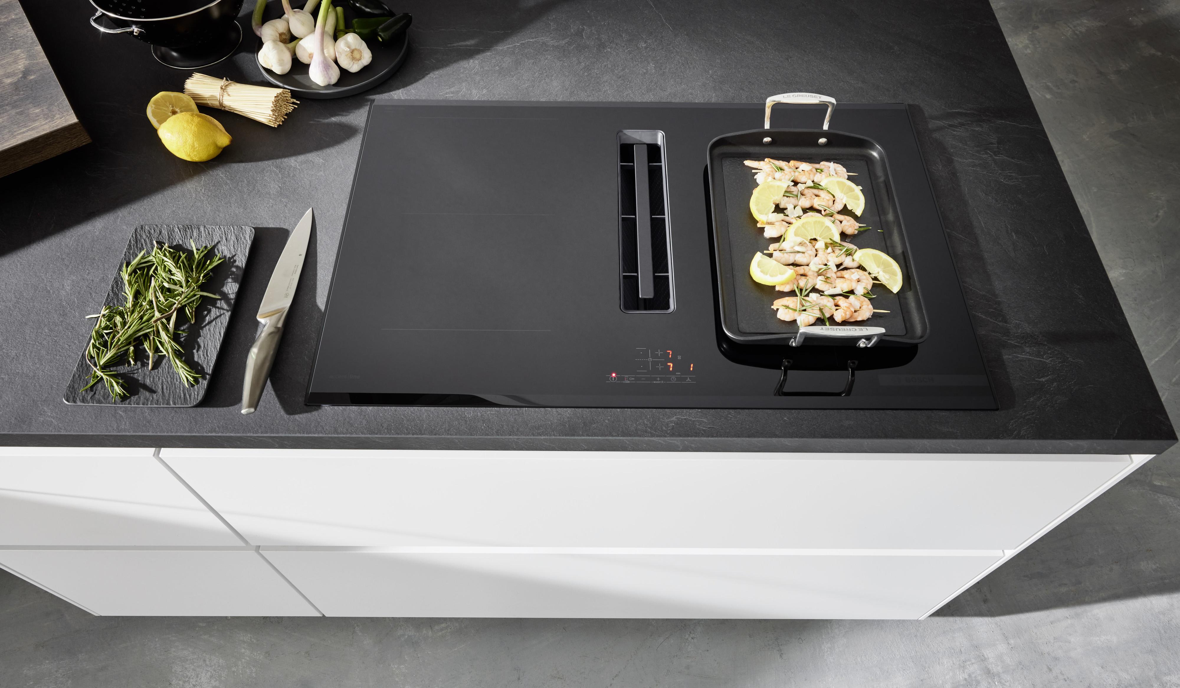 Schwarzweiße Kochinsel weiße grifflose Fronten APL Schiefer-Optik mattschwarzes Kochfeld mit Muldenlüfter